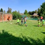 Niños jugando a la pelota en una cancha de pasto