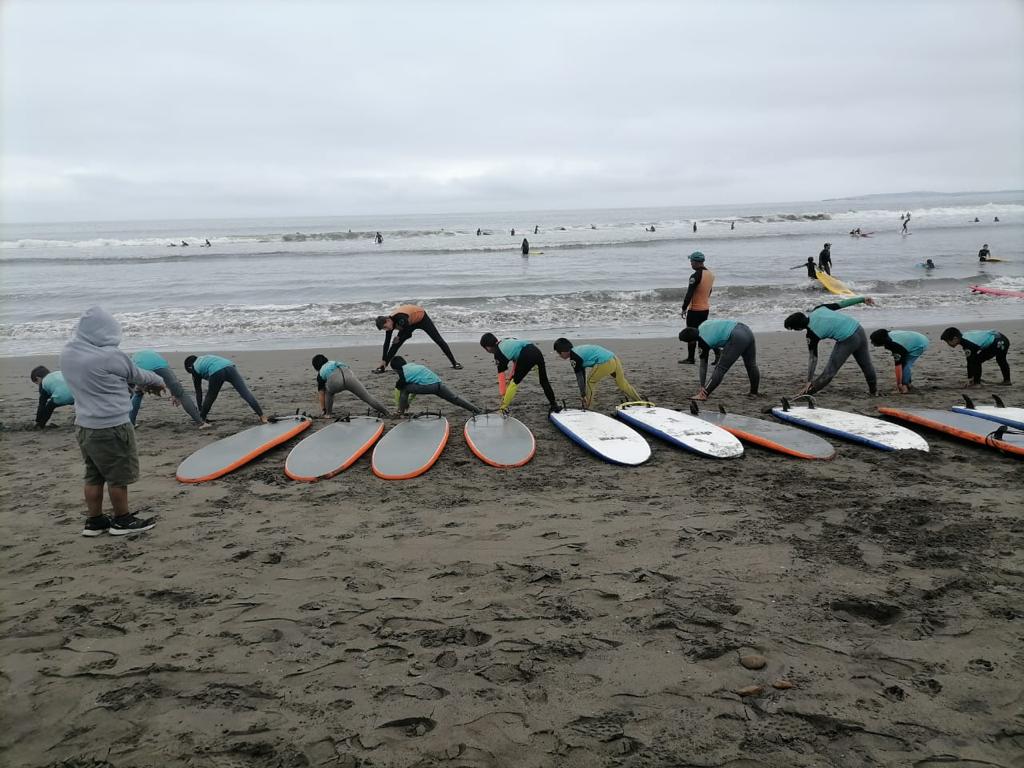 Niños en la playa, estando en la arena, pre-calentando para una clase de surf